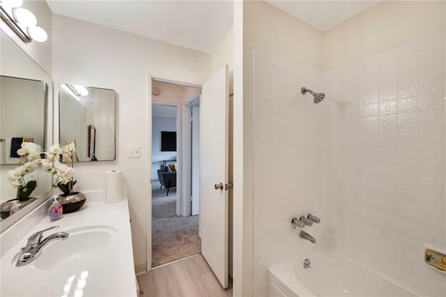 bathroom with tiled shower / bath combo, vanity, and wood-type flooring