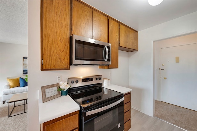 kitchen with a textured ceiling, light hardwood / wood-style floors, and stainless steel appliances