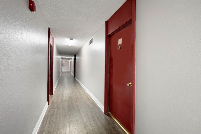 corridor featuring wood-type flooring and a textured ceiling