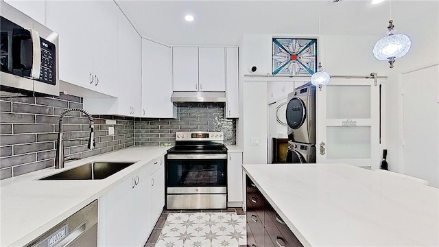 kitchen with hanging light fixtures, appliances with stainless steel finishes, light countertops, and a sink