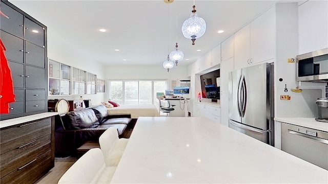 kitchen with white cabinetry, appliances with stainless steel finishes, hanging light fixtures, and dark wood-type flooring