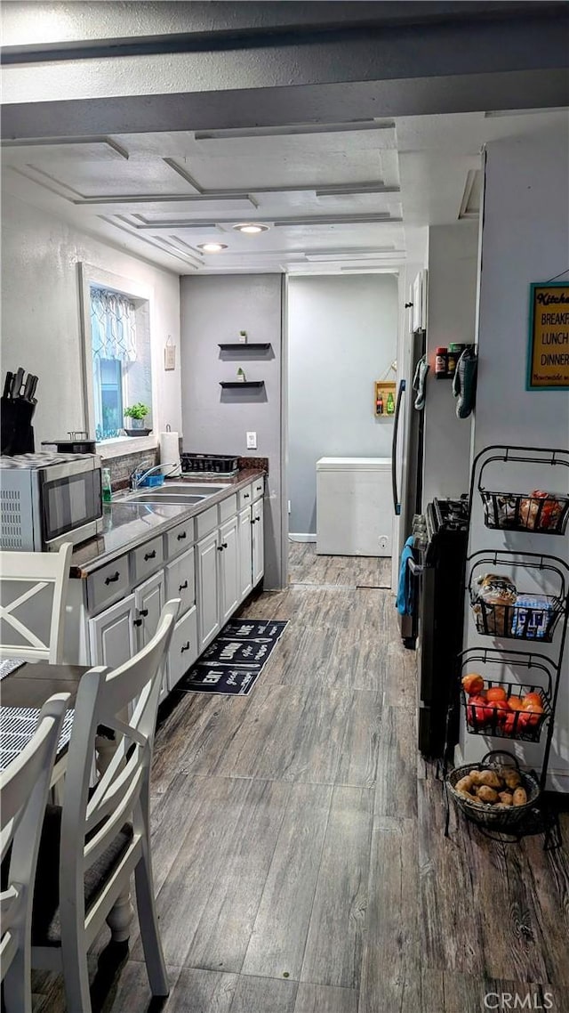 kitchen with hardwood / wood-style floors, white cabinets, and sink