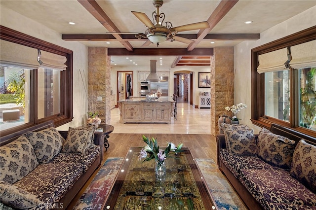 living room with ceiling fan, light hardwood / wood-style flooring, coffered ceiling, and beamed ceiling