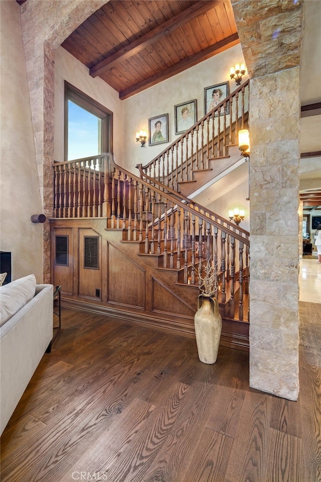 stairs with wooden ceiling, beamed ceiling, and hardwood / wood-style floors