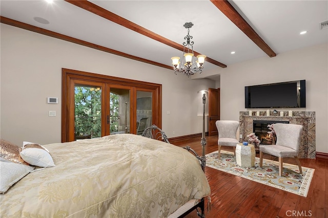 bedroom with a premium fireplace, beam ceiling, hardwood / wood-style flooring, and a notable chandelier