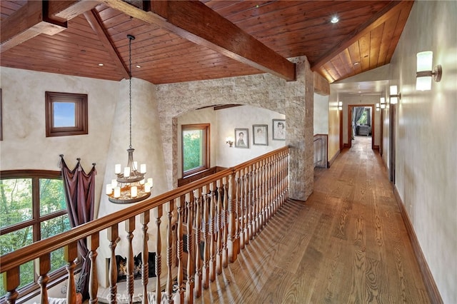 hall featuring hardwood / wood-style floors, wood ceiling, a healthy amount of sunlight, a notable chandelier, and beam ceiling