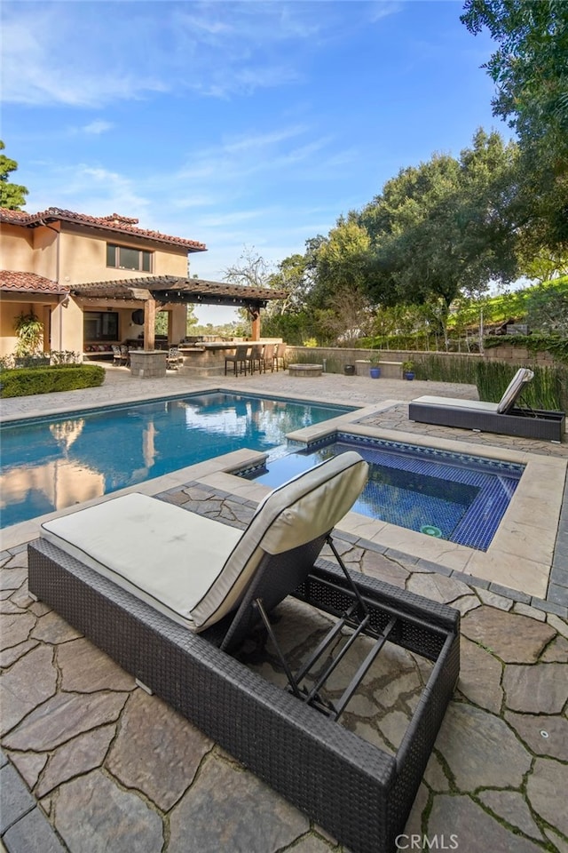 view of swimming pool featuring a bar, a patio, and an in ground hot tub