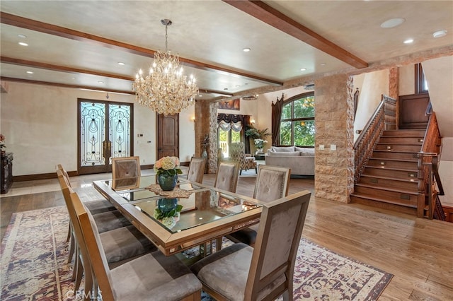 dining room featuring a notable chandelier, beam ceiling, french doors, and light wood-type flooring