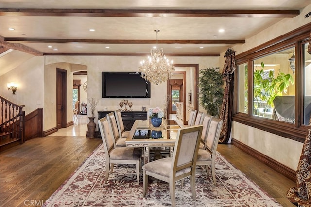 dining space featuring hardwood / wood-style floors, beam ceiling, and an inviting chandelier