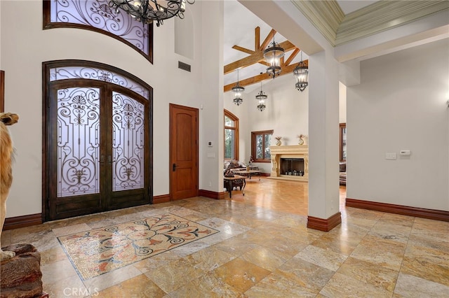 foyer entrance with french doors, a high ceiling, and ornamental molding