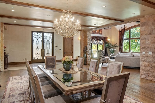 dining room featuring light wood-type flooring, a chandelier, french doors, and beamed ceiling