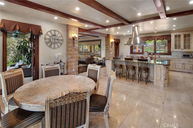 dining space with sink and beamed ceiling