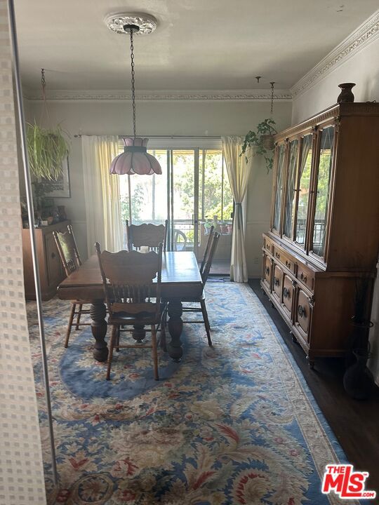 dining space featuring a healthy amount of sunlight, ornamental molding, and dark hardwood / wood-style flooring