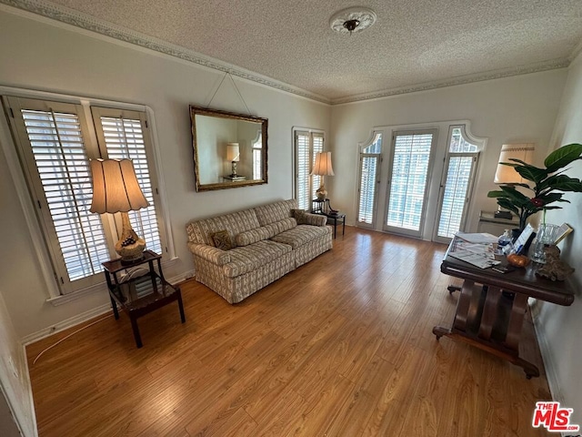 living room with a textured ceiling, crown molding, and wood-type flooring