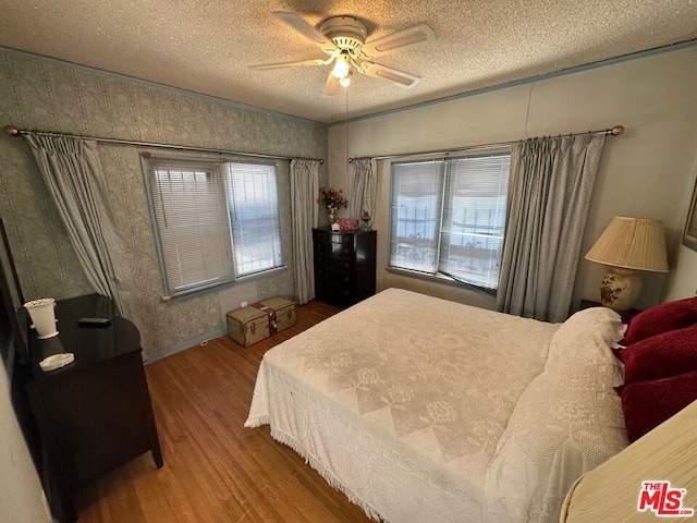 bedroom featuring hardwood / wood-style floors, a textured ceiling, and ceiling fan