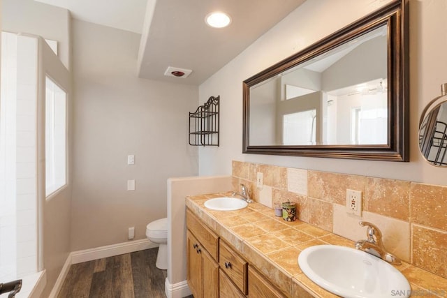 bathroom featuring wood-type flooring, vanity, toilet, and decorative backsplash