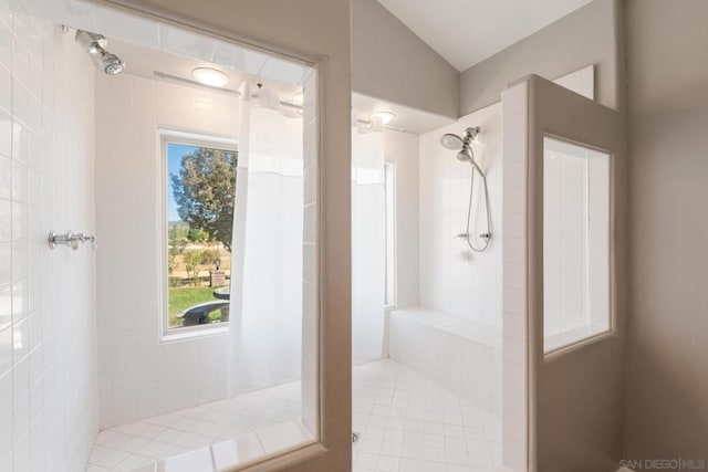 bathroom featuring a tile shower and vaulted ceiling