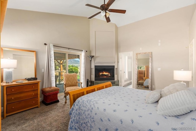 bedroom featuring access to exterior, a tiled fireplace, carpet floors, high vaulted ceiling, and ceiling fan