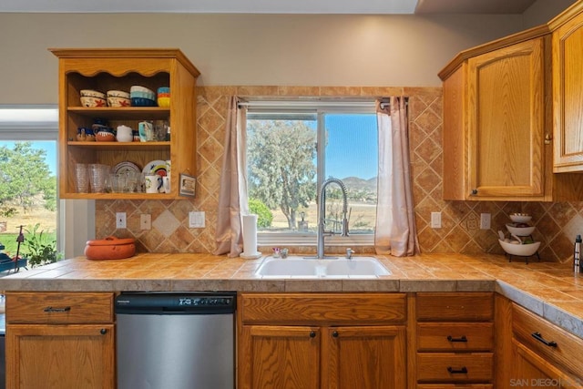 kitchen with tile counters, sink, tasteful backsplash, and stainless steel dishwasher