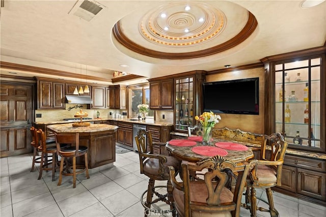 tiled dining area with crown molding and a tray ceiling