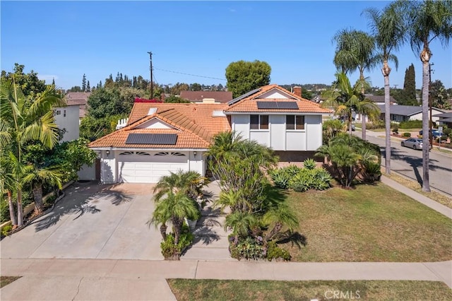 view of front of home featuring a garage, a front yard, and solar panels