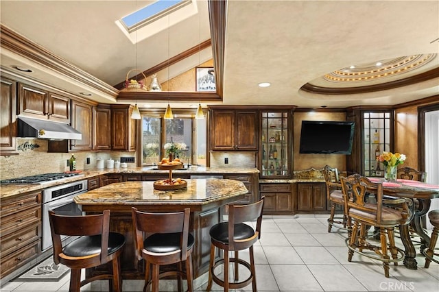 kitchen with a skylight, stainless steel appliances, decorative backsplash, crown molding, and light stone counters