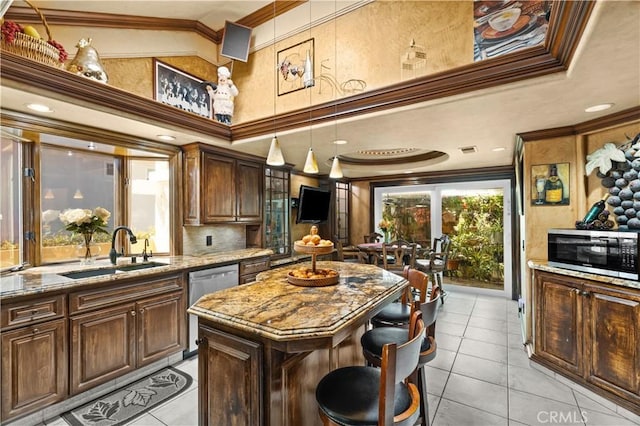 kitchen featuring appliances with stainless steel finishes, a kitchen island, crown molding, and sink