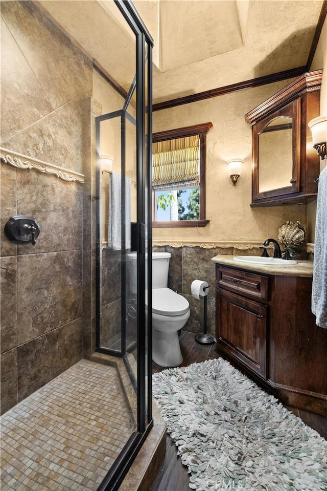 bathroom with toilet, a shower with shower door, hardwood / wood-style flooring, and vanity