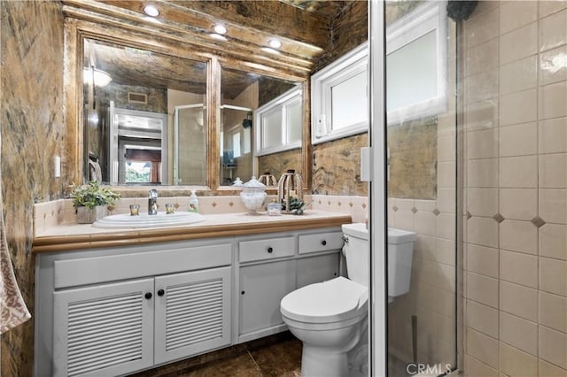 bathroom with a shower with shower door, vanity, tile walls, and beam ceiling