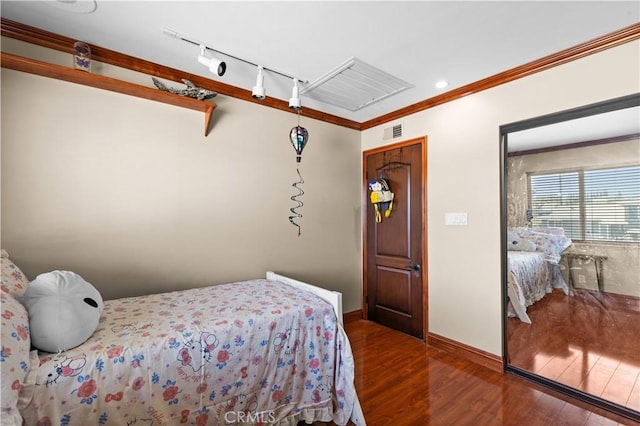 bedroom featuring dark hardwood / wood-style flooring, ornamental molding, and rail lighting