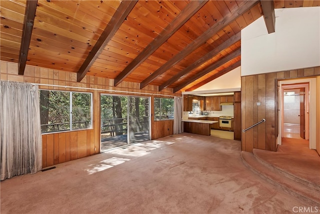 unfurnished living room featuring beamed ceiling, wood ceiling, wood walls, and carpet flooring