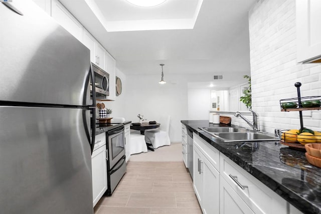 kitchen featuring dark stone counters, sink, white cabinetry, hanging light fixtures, and stainless steel appliances