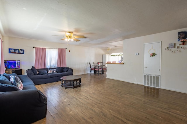 living room featuring dark hardwood / wood-style flooring, ceiling fan, and a wealth of natural light