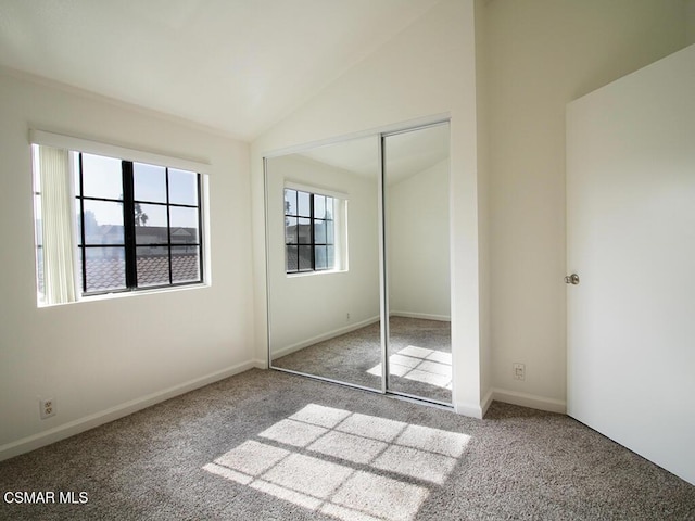 unfurnished bedroom featuring light carpet, a closet, and lofted ceiling