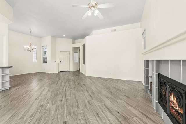 unfurnished living room with a tile fireplace, light hardwood / wood-style floors, and ceiling fan with notable chandelier