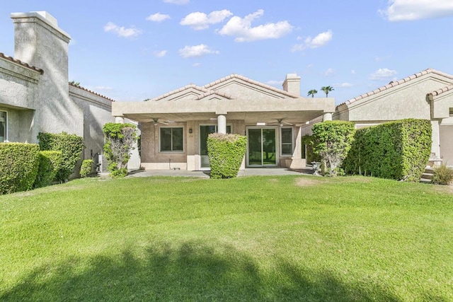 back of property featuring ceiling fan, a patio area, and a lawn