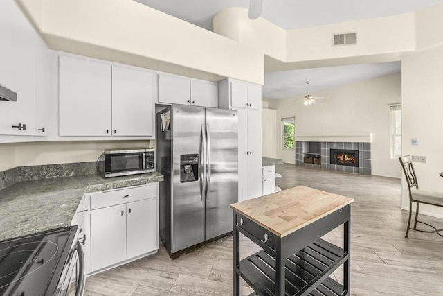 kitchen with white cabinetry, a fireplace, ceiling fan, and stainless steel appliances