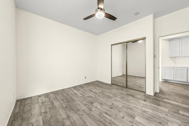 unfurnished bedroom featuring a closet, light hardwood / wood-style flooring, and ceiling fan