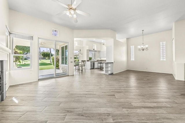 unfurnished living room featuring ceiling fan with notable chandelier and light hardwood / wood-style flooring