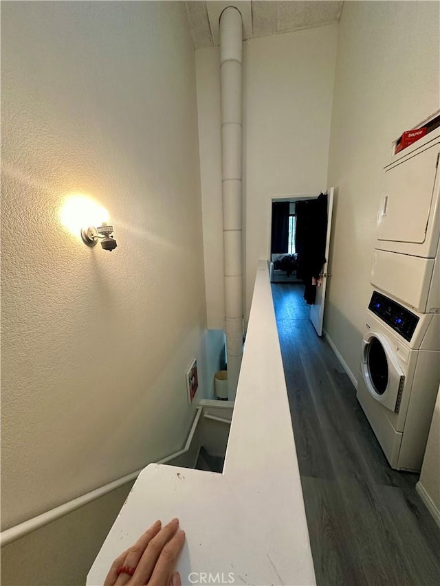 clothes washing area with stacked washer / drying machine and dark wood-type flooring