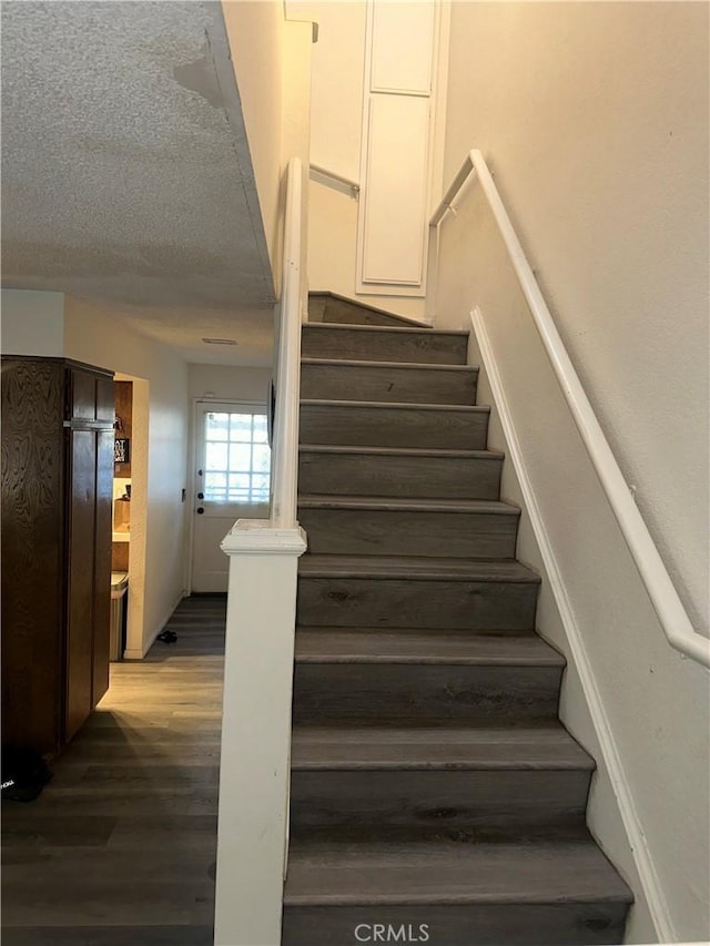 stairway with hardwood / wood-style flooring and a textured ceiling