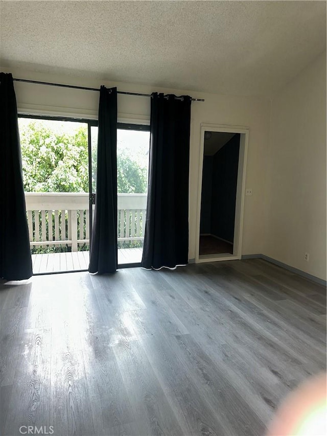 spare room featuring a textured ceiling, baseboards, and wood finished floors