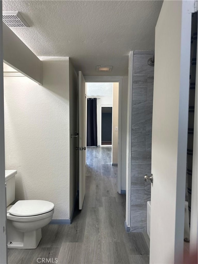 full bathroom with visible vents, a textured wall, toilet, wood finished floors, and a textured ceiling