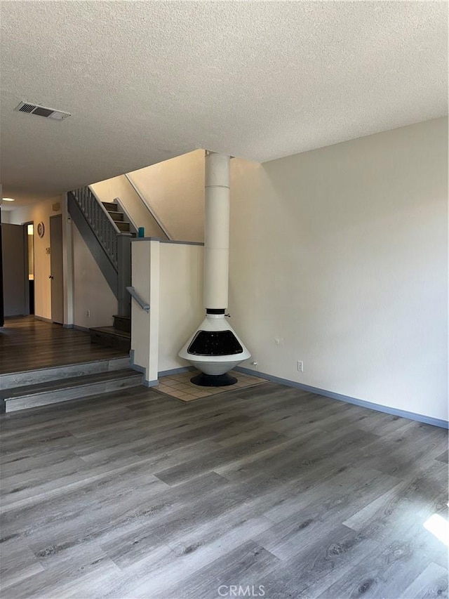 unfurnished living room with baseboards, stairs, visible vents, and wood finished floors