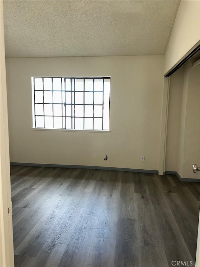 empty room featuring plenty of natural light, a textured ceiling, and wood finished floors