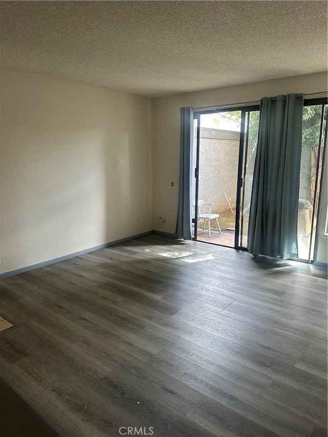 unfurnished room featuring a textured ceiling, dark wood-type flooring, and baseboards