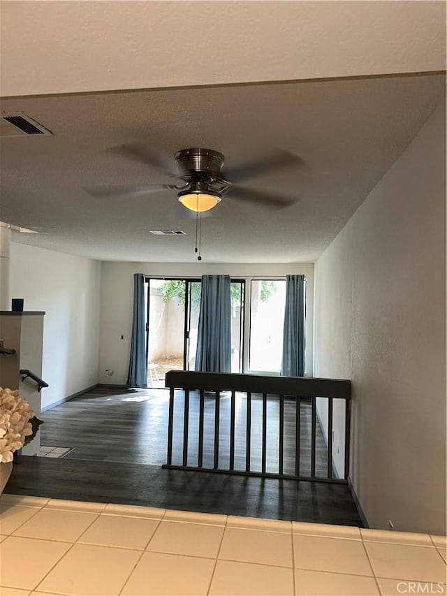 hallway with baseboards, visible vents, and tile patterned floors