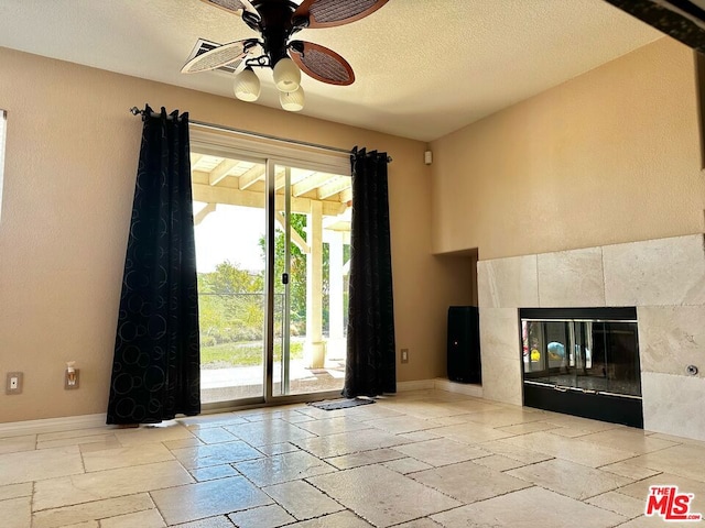 unfurnished living room featuring a textured ceiling, a tile fireplace, and ceiling fan