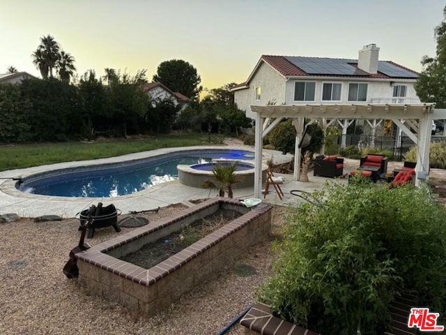 pool at dusk with a patio, a pergola, an in ground hot tub, and outdoor lounge area