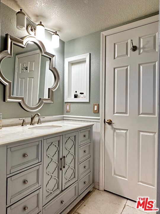 bathroom featuring tile patterned flooring, a textured ceiling, and vanity